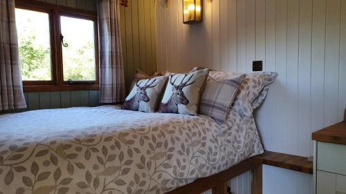 a bedroom with a bed with a comforter with deer pillows at Sika hut in Wareham