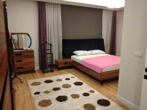 een slaapkamer met een bed, een spiegel en een tapijt bij Sakın bir ortamda 3 odalı villa in Antalya