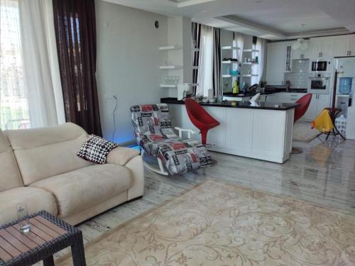 Sakın bir ortamda 3 odalı villa في أنطاليا: غرفة معيشة مع أريكة ومطبخ