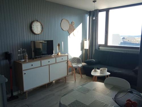 salon z telewizorem, kanapą i zegarem w obiekcie Chez Loïc et Mélanie w mieście Besse-et-Saint-Anastaise