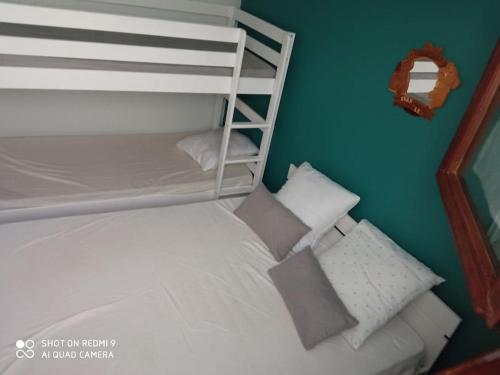 - une petite chambre avec des lits superposés blancs et des oreillers dans l'établissement Chez Loïc et Mélanie, à Besse-et-Saint-Anastaise