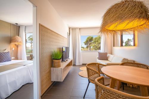 a hotel room with a bed and a table and chairs at Migjorn Ibiza Suites & Spa in Playa d'en Bossa
