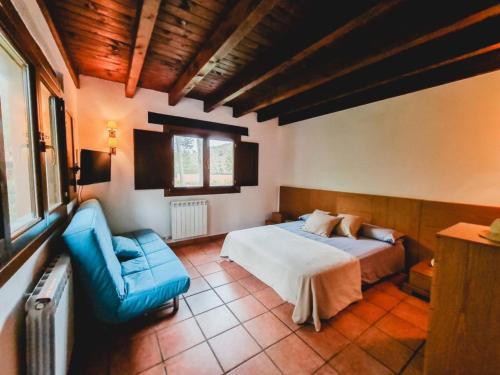 1 dormitorio con 1 cama y 1 silla azul en El Molino de la Pastora, en Valacloche