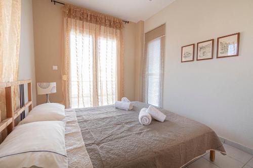 een slaapkamer met een groot bed en handdoeken bij Antonia Apartment by RentalsPro- Nea Moudania Halkidiki in Nea Moudania