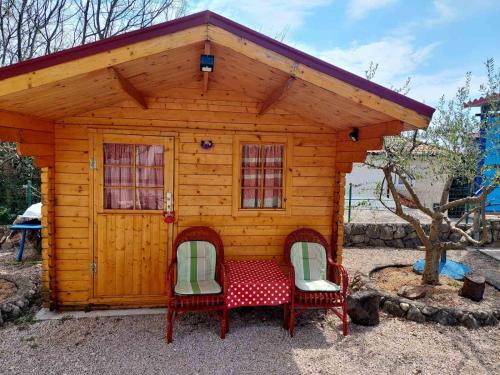 a small wooden house with two chairs and a table at Rooms Hodanić in Krk