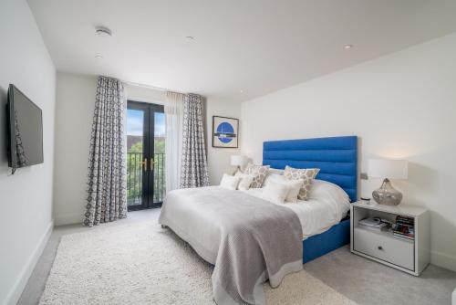 a bedroom with a blue bed and a window at ALTIDO Spectacular flat overlooking river Thames in London