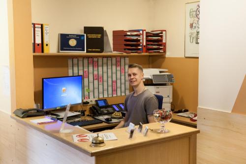 un homme assis à un bureau avec un ordinateur dans l'établissement Hotel Garni Haus zum Gutenberg, à Hallbergmoos