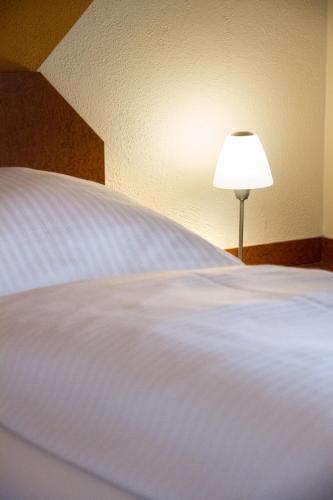 a large white bed with a lamp next to it at Hotel Garni Haus zum Gutenberg in Hallbergmoos