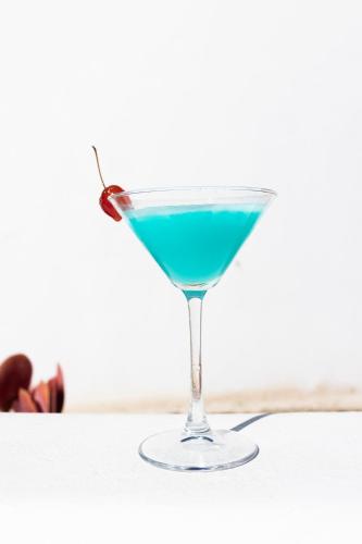 a blue drink in a martini glass on a table at Casa Vitae Suites in Kamari