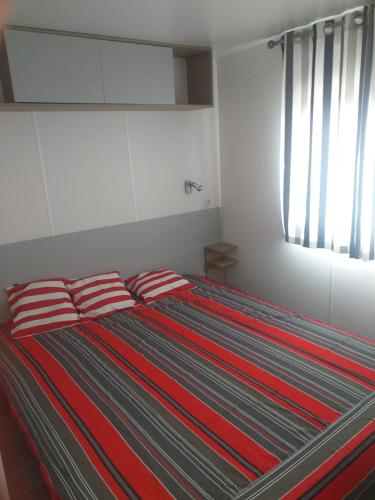 a bed with red and blue striped pillows in a bedroom at DOMAINE DE LA GRANGE DES CHAMPS in Lorris