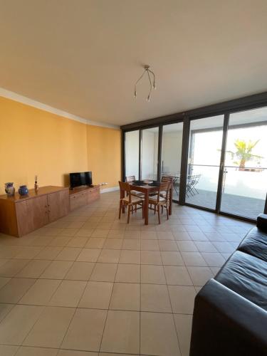 a living room with a table and chairs and a television at San Lorenzo Marina Apartment in San Lorenzo al Mare