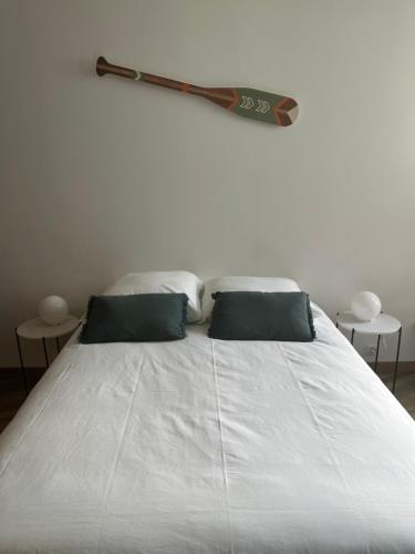 a white bed with two pillows and a bat on the wall at Vivez la Marina - Plage - Port de plaisance in Le Havre