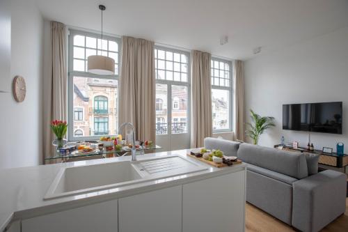 a white kitchen with a large sink and a couch at Sweet Inn - Churchill in Brussels
