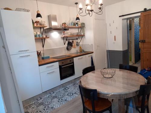 Una cocina con una mesa y un refrigerador blanco. en Appartement rue de la cascade 64440 Eaux-Bonnes, en Eaux-Bonnes