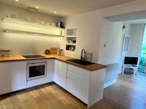 a kitchen with white cabinets and a wooden floor at 4 Balvaig Cottage in Stirling