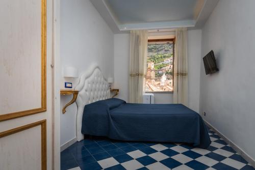 ein Schlafzimmer mit einem blauen Bett und einem Fenster in der Unterkunft Moon'n Sea in Minori