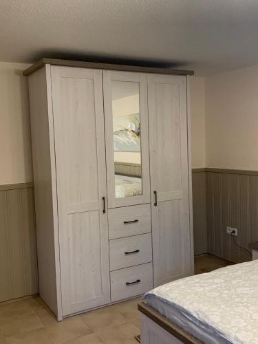 a bedroom with a white cabinet with a mirror at Privatzimmer Guhl in Munster im Heidekreis