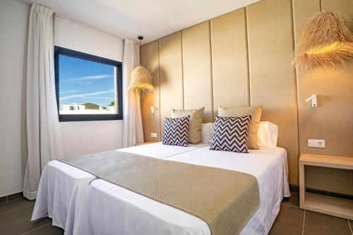 a bedroom with a large bed and a large window at Migjorn Ibiza Suites & Spa in Playa d'en Bossa