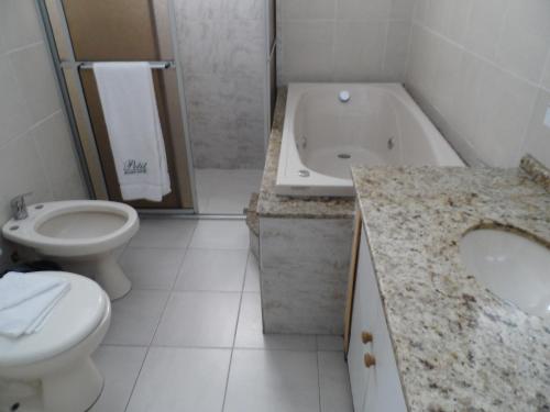 a bathroom with a toilet and a sink and a tub at Petit Rivera Hotel in Rivera