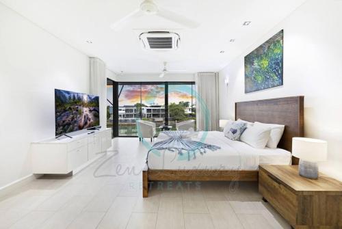 a bedroom with a king sized bed and a tv at ZenLux: 4BR Bayview Mansion Infinity Pool + Cinema in Stuart Park