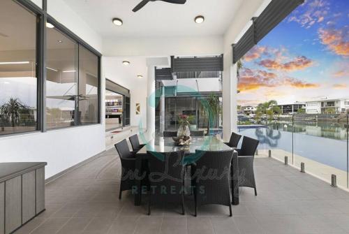 a dining room with a glass table and chairs at ZenLux: 4BR Bayview Mansion Infinity Pool + Cinema in Stuart Park