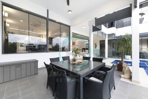 a dining room with a glass table and chairs at ZenLux: 4BR Bayview Mansion Infinity Pool + Cinema in Stuart Park