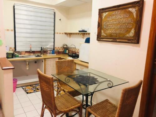 cocina con mesa de cristal y sillas en PUTRI HOMESTAY SEAVIEW PD, en Port Dickson