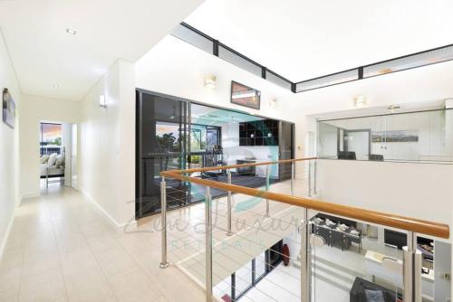 uma escada numa casa com corrimão de vidro em ZenLux: 4BR Bayview Mansion Infinity Pool + Cinema em Stuart Park