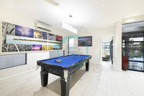 a pool table in a living room with paintings at ZenLux: 4BR Bayview Mansion Infinity Pool + Cinema in Stuart Park