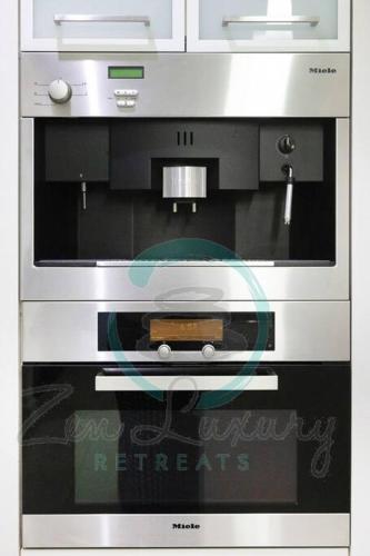 a microwave oven with a black and white at ZenLux: 4BR Bayview Mansion Infinity Pool + Cinema in Stuart Park