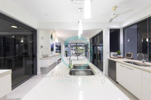 a kitchen with white cabinets and a sink at ZenLux: 4BR Bayview Mansion Infinity Pool + Cinema in Stuart Park