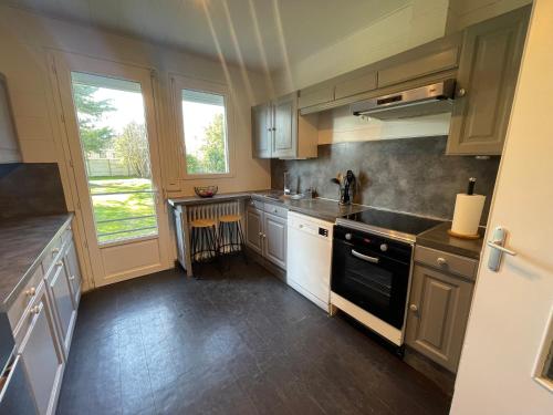 La cuisine est équipée de placards blancs et d'un four avec plaques de cuisson noires. dans l'établissement La Maison Portaise, à Port-en-Bessin-Huppain