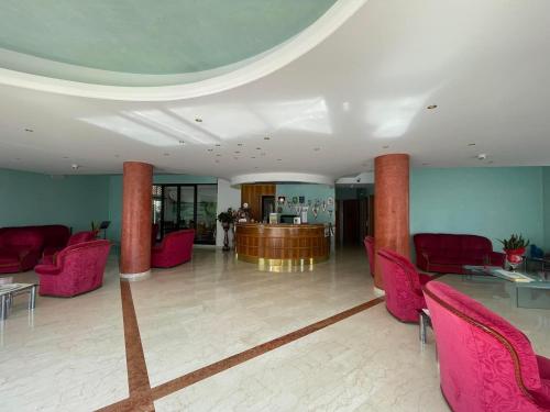 a lobby with pink chairs and a bar in the background at Hotel Cristina in Chianciano Terme