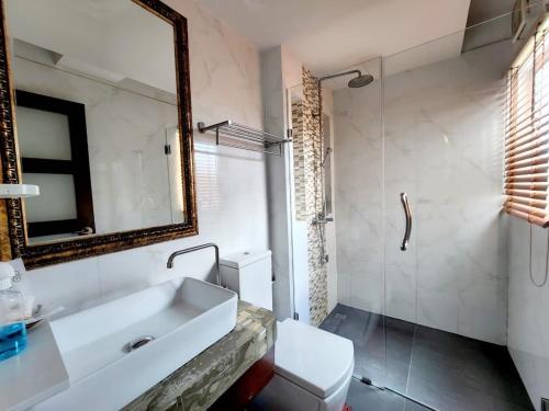 ein Badezimmer mit einem Waschbecken, einem Spiegel und einem WC in der Unterkunft Nordwind Hotel in Chiang Mai