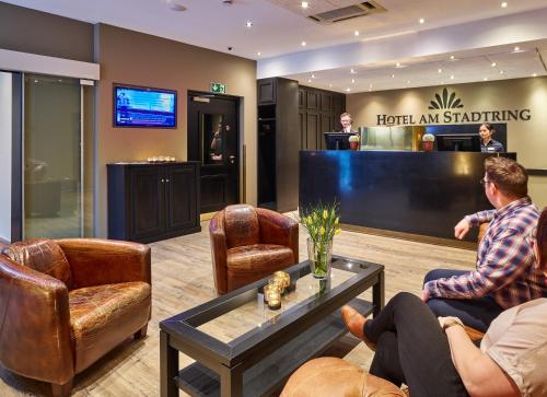 zwei Männer in einer Lobby mit einem Flachbild-TV in der Unterkunft Hotel-Hofbräu am Stadtring in Nordhorn