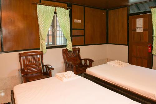 two beds in a room with two chairs and a window at Haadrin Resort in Haad Rin