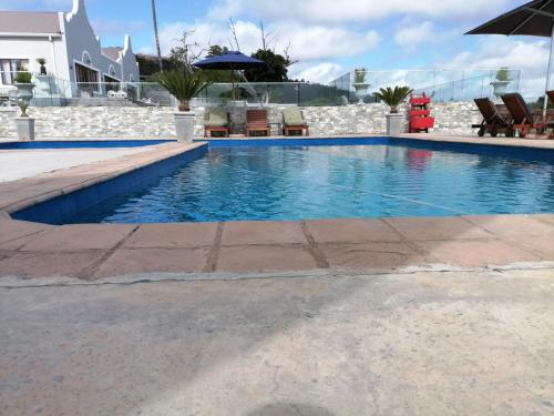 a swimming pool with chairs and an umbrella at Issaquena Heights Boutique Hotel in Knysna