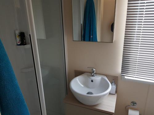 y baño con lavabo blanco y espejo. en 6 BERTH DELUXE CARAVAN PALM GROVE 42, en Chapel St. Leonards