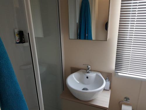 a bathroom with a white sink and a mirror at 6 BERTH DELUXE CARAVAN PALM GROVE 42 in Chapel Saint Leonards