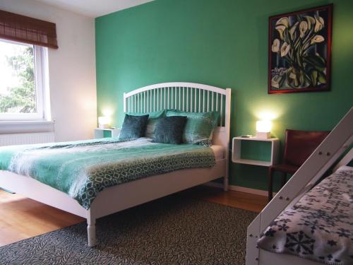 Baker's Pond Apartment Two في فيلدين ام ورثرسي: غرفة نوم بجدران خضراء وسرير بمخدات زرقاء