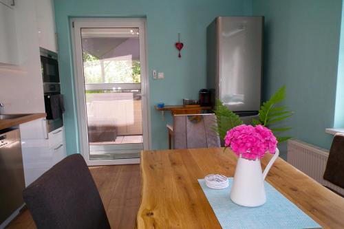 a table with a vase with pink flowers on it at Baker's Pond Apartment Two in Velden am Wörthersee