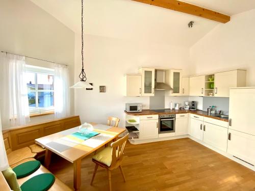 cocina con armarios blancos y mesa de madera en Suite Heidi am Golfplatz Uttlau-Haarbach, en Haarbach