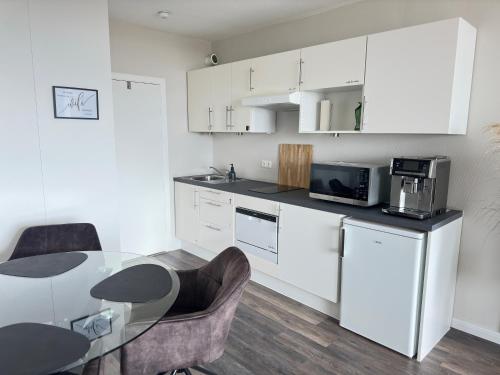 a kitchen with white cabinets and a table with chairs at Timmendomizil - schöne Ferienwohnung in bester Lage - Sonnenseite in Timmendorfer Strand