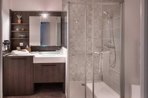 uma casa de banho com um chuveiro e um lavatório. em Domitys Le 225 em Levallois-Perret