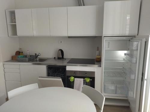 La cuisine est équipée de placards blancs et d'un réfrigérateur blanc. dans l'établissement Apartments B&M, à Sežana