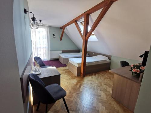 a small room with a bed and a desk and chairs at Hotel Zieliniec in Poznań