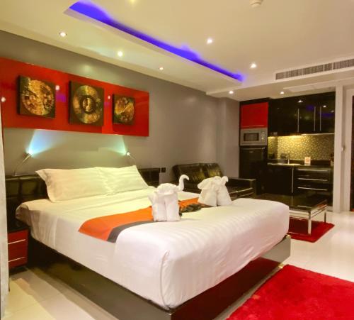 a bedroom with a large white bed and a kitchen at Absolute Bangla Suites in Patong Beach