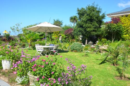 a garden with a table and an umbrella and flowers at Serenity Ocean Lodge in Wilderness
