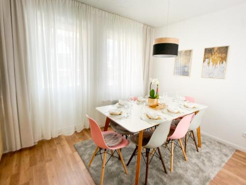 a dining room with a white table and pink chairs at M-Style 02 Apartment mit Balkon 24h Self-Check-In, Free Parking, Netflix in Nürnberg