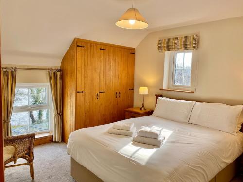 a bedroom with a large white bed and two windows at Shamrock Cottage in Aghnablaney